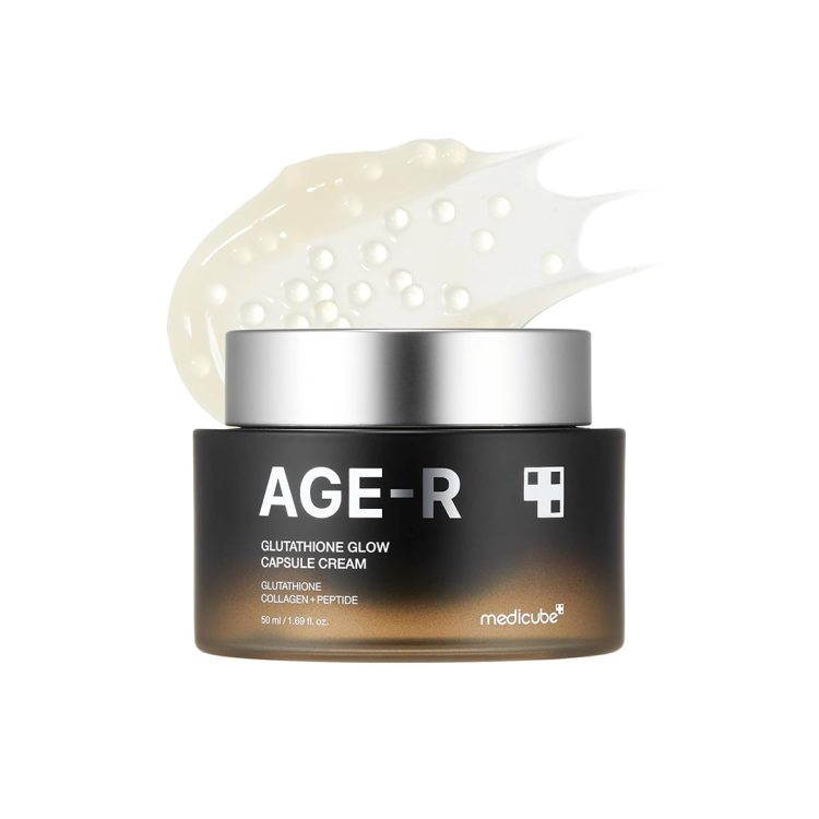 Стаклено пакување од крем Medicube AGE-R Glutathione Glow Capsule Cream со капсулирани зрнца, поставено пред текстура од кремот во позадина. Glass jar of Medicube AGE-R Glutathione Glow Capsule Cream with visible capsules, displayed in front of a cream texture background.