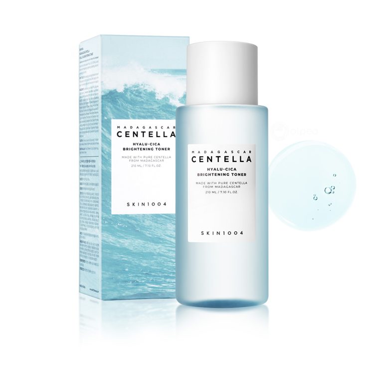 Skin1004 Madagascar Centella Hyalu-Cica Brightening Toner 210ml со амбалажа и текстура – хидратантен и осветлувачки тонер со центела и хијалуронска киселина, прикажан со светло сина течност и оригинално пакување. Skin1004 Madagascar Centella Hyalu-Cica Brightening Toner 210ml with packaging and texture – hydrating and brightening toner featuring centella and hyaluronic acid, shown with light blue liquid and original box.