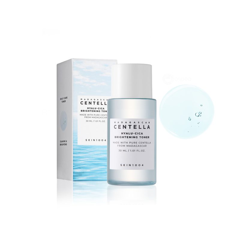 Skin1004 Madagascar Centella Hyalu-Cica Brightening Toner 30ml со амбалажа и текстура – хидратантен и осветлувачки тонер со центела и хијалуронска киселина, прикажан во мини верзија со сина течност и оригинално пакување. Skin1004 Madagascar Centella Hyalu-Cica Brightening Toner 30ml with packaging and texture – hydrating and brightening toner with centella and hyaluronic acid, shown in mini version with blue liquid and original box.