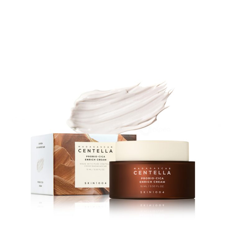 Мини пакување од SKIN1004 Madagascar Centella Probio-Cica Enrich Cream 15ml со тегличка и кутиија прикажани заедно со текстура од кремата во позадина. Mini packaging of SKIN1004 Madagascar Centella Probio-Cica Enrich Cream 15ml with jar and box shown together, along with cream texture in the background.