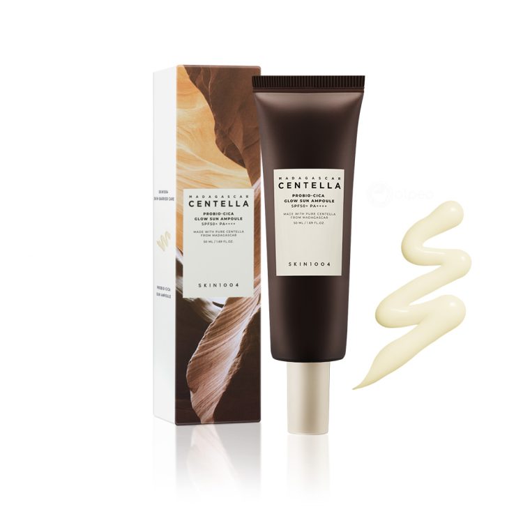 SKIN1004 Madagascar Centella Probio-Cica Glow Sun Ampoule SPF50+ PA++++ – Туба со заштитен крем за лице со пробиотици и центела, покрај кутија со природен дизајн и пример од кремот со сјајна текстура. SKIN1004 Madagascar Centella Probio-Cica Glow Sun Ampoule SPF50+ PA++++ – Tube of probiotic and centella-infused facial sunscreen next to a nature-inspired box and a swatch of the glowing cream texture.