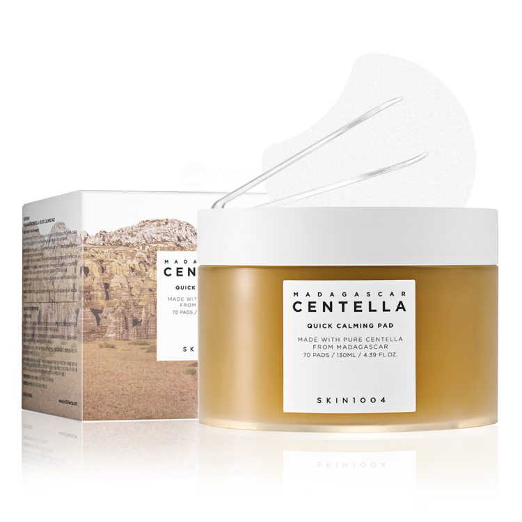 SKIN1004 Madagascar Centella Quick Calming Pad – пакување со 70 тонер тампони со центела од Мадагаскар, прикажано со кутија, пинцета и една извадена подлога. SKIN1004 Madagascar Centella Quick Calming Pad – container with 70 toner pads made with Centella from Madagascar, shown with box, tweezers, and one pad displayed.